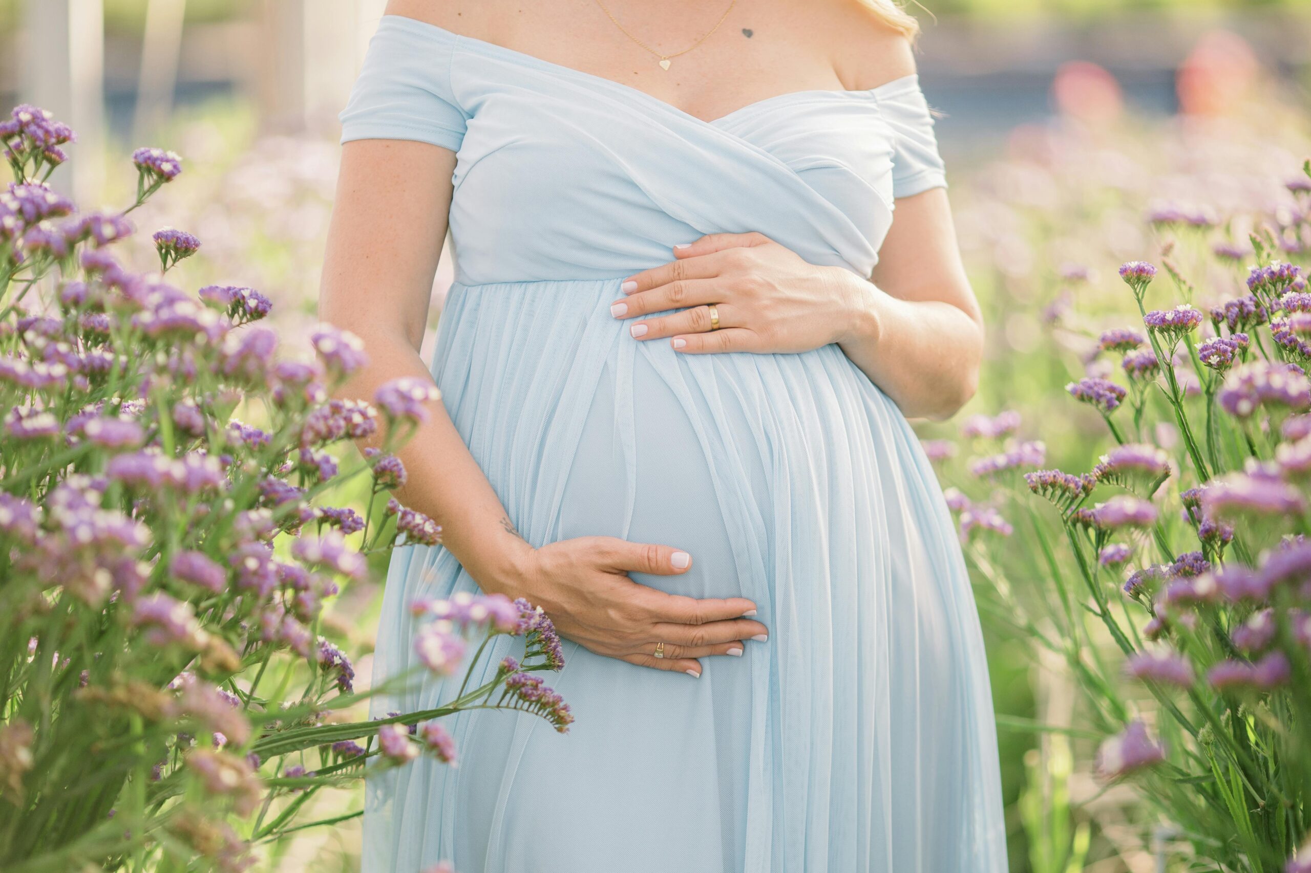 Roseburg Oregon maternity photographer at Discovery Garden with woman in blue dress and flowers.